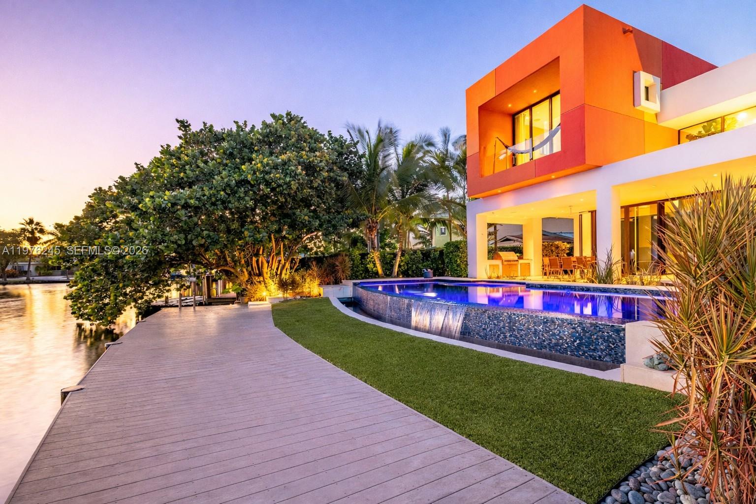 A modern house with an orange exterior, infinity pool, and wooden deck overlooking a canal — 2101 NE 20th Ave, Wilton Manors FL 33305, WILTON MANORS, FL