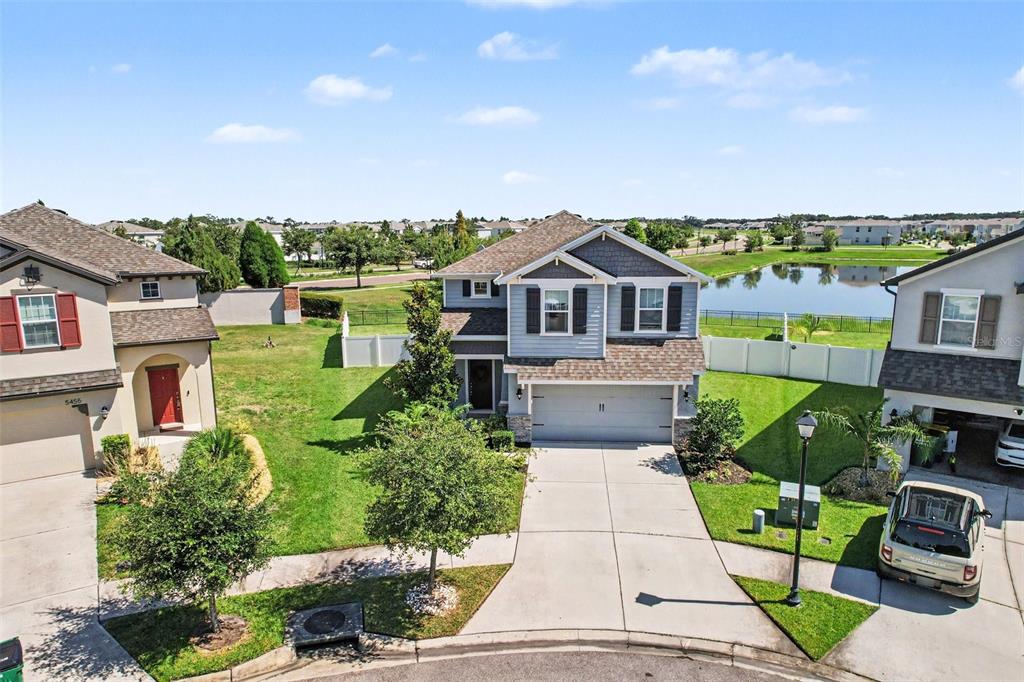 An aerial view of a two-story suburban house with a driveway and a backyard pond — 5463 LITTLE STREAM LANE, WESLEY CHAPEL, FL