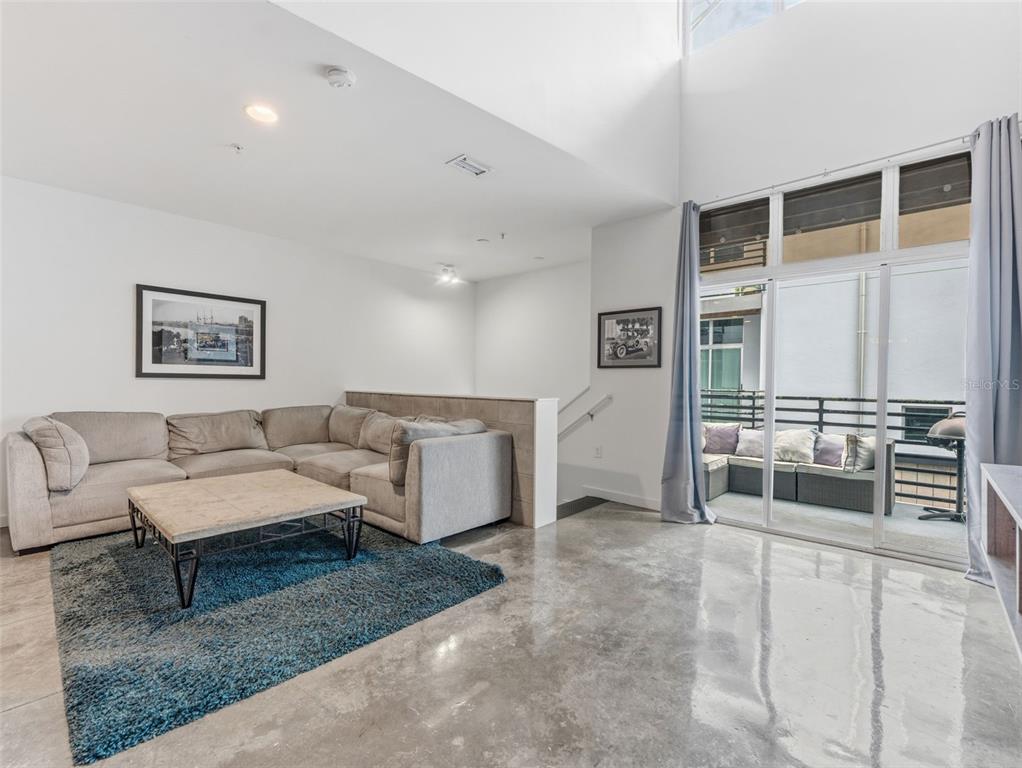 A living room features a sectional sofa, a blue rug, concrete floors, and a balcony — 5008 S MACDILL AVENUE UNIT 16, TAMPA, FL