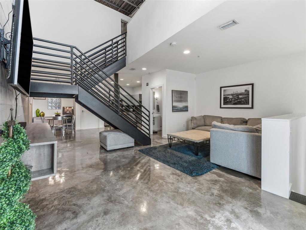 A modern living room features a metal staircase, polished concrete floors, and high ceilings — 5008 S MACDILL AVENUE UNIT 16, TAMPA, FL