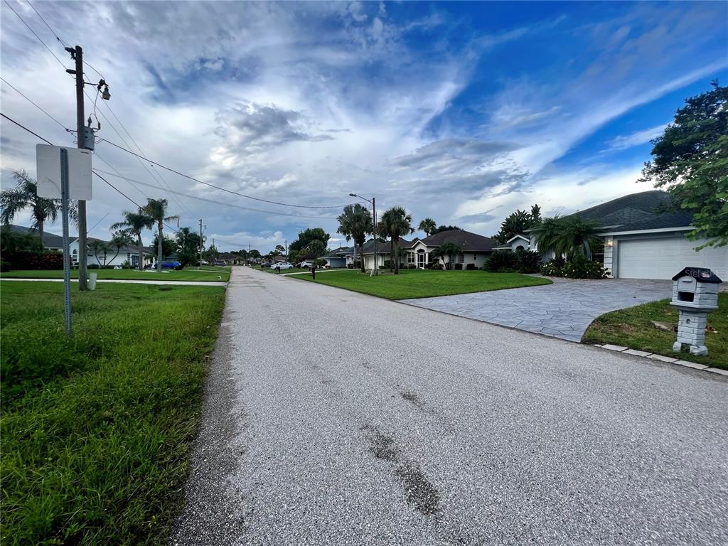 A residential street view featuring houses, manicured lawns, palm trees, and a mailbox — 11 SPORTSMAN ROAD, ROTONDA WEST, FL