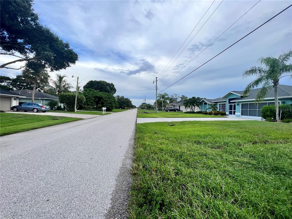 A street view of a residential neighborhood with houses, lawns, and a paved road — 11 SPORTSMAN ROAD, ROTONDA WEST, FL