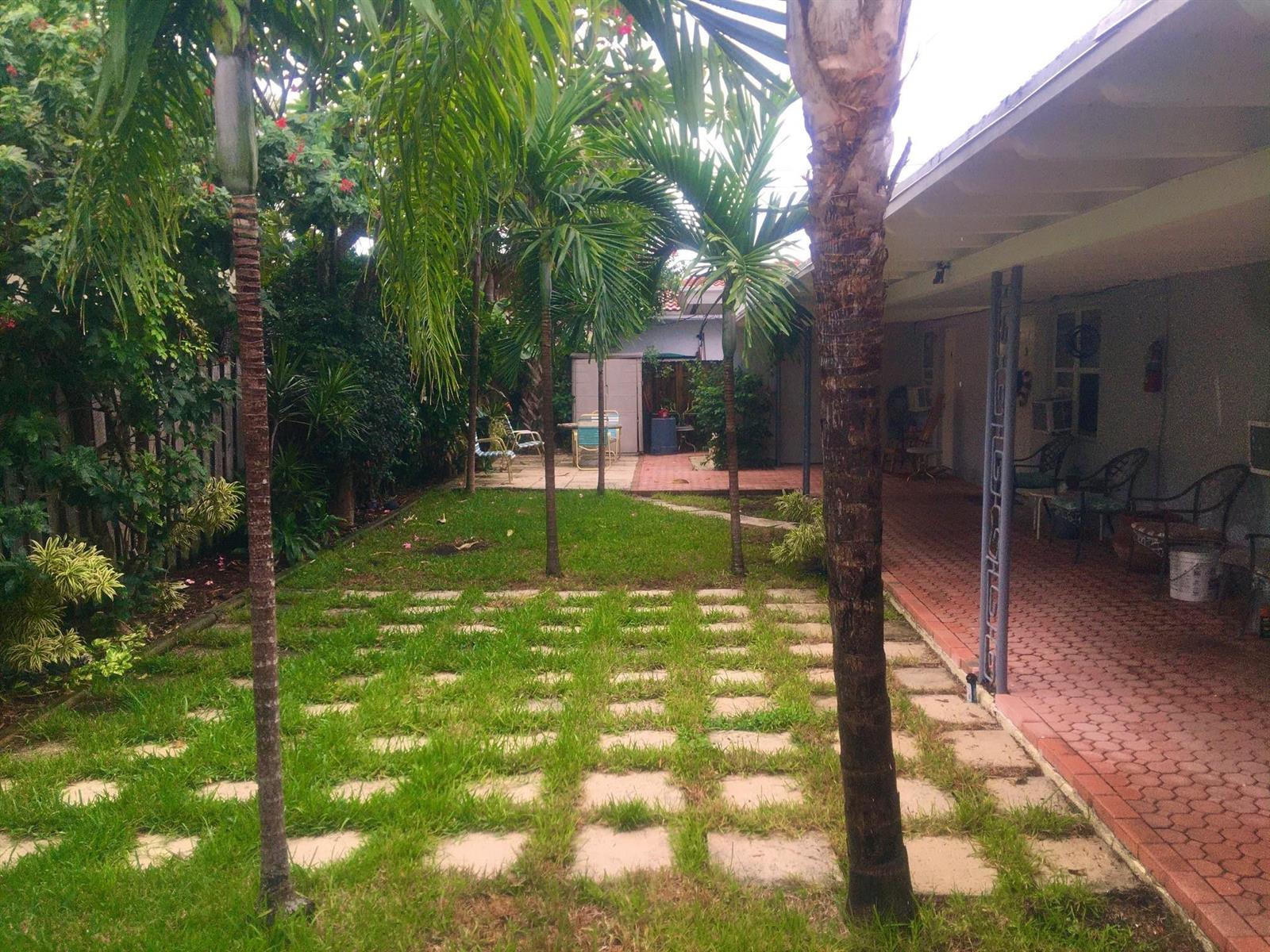 A backyard features a brick patio, a grid of stone pavers, and several palm trees — FORT LAUDERDALE, FL