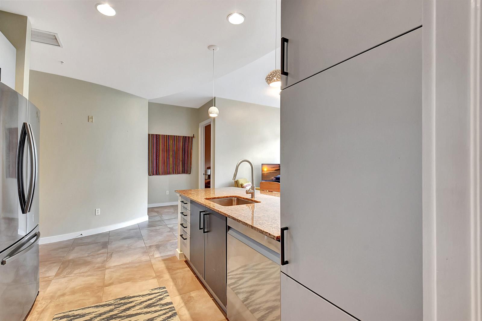 A kitchen features a granite-topped island, stainless steel appliances, and light-colored cabinetry — 365 SE 6th Avenue # 204, Delray Beach FL 33483, DELRAY BEACH, FL