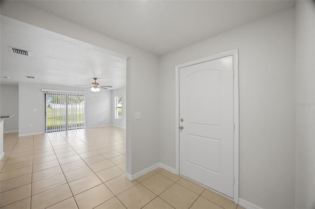 A bright entryway with tile flooring leads into an open-concept living area with sliding doors — 8512 SILVERBELL LOOP, BROOKSVILLE, FL