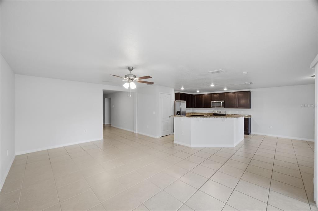 An open-concept kitchen with dark cabinets and a breakfast bar overlooks a tiled living area — 8512 SILVERBELL LOOP, BROOKSVILLE, FL