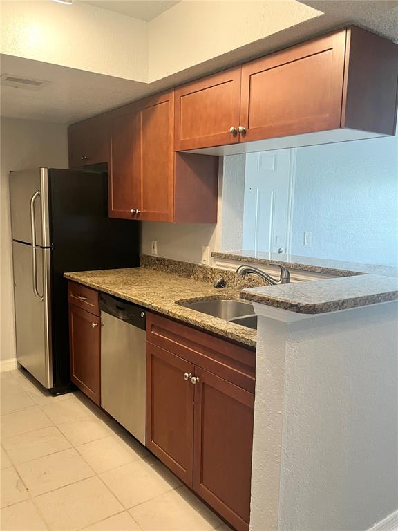 A kitchen features wood cabinets, granite countertops, a stainless steel dishwasher, and a black refrigerator — 10200 GANDY BOULEVARD N UNIT 813, ST PETERSBURG, FL