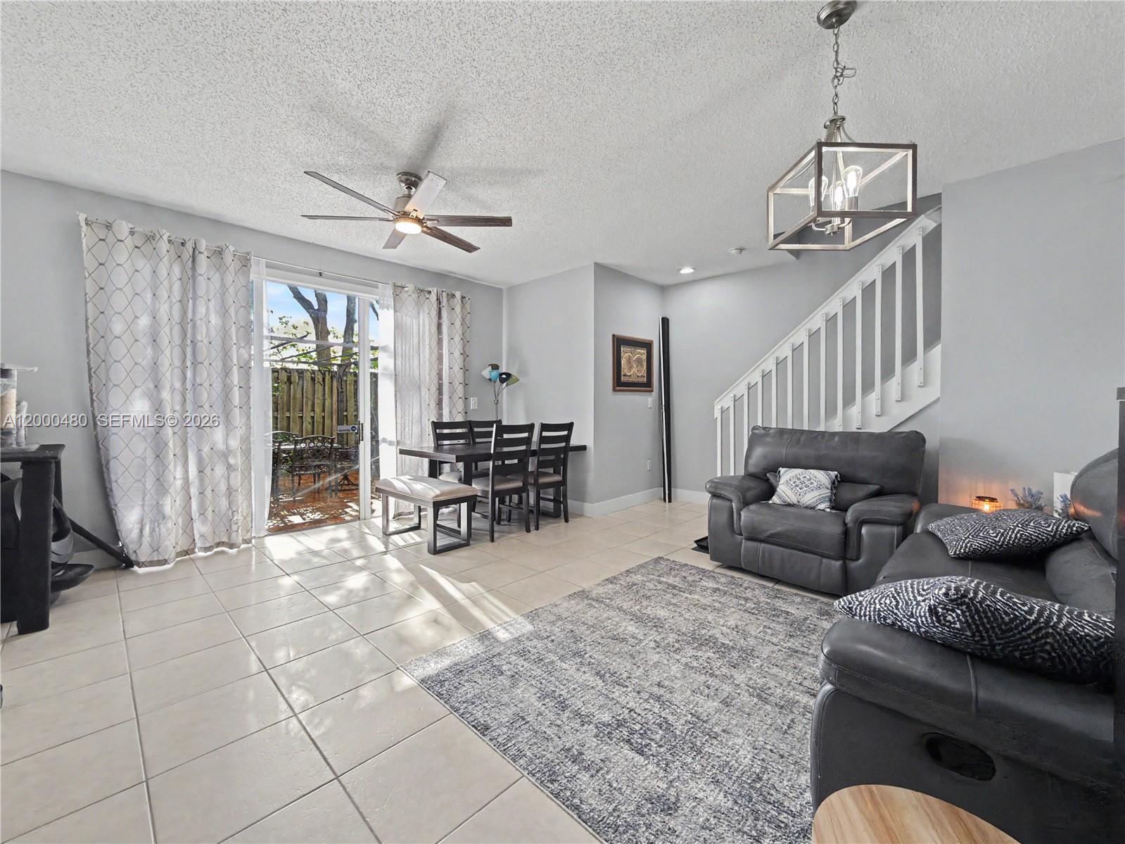 A living and dining area features tile floors, a ceiling fan, and a sliding glass door — 1033 NE 42nd Pl, Homestead FL 33033, HOMESTEAD, FL