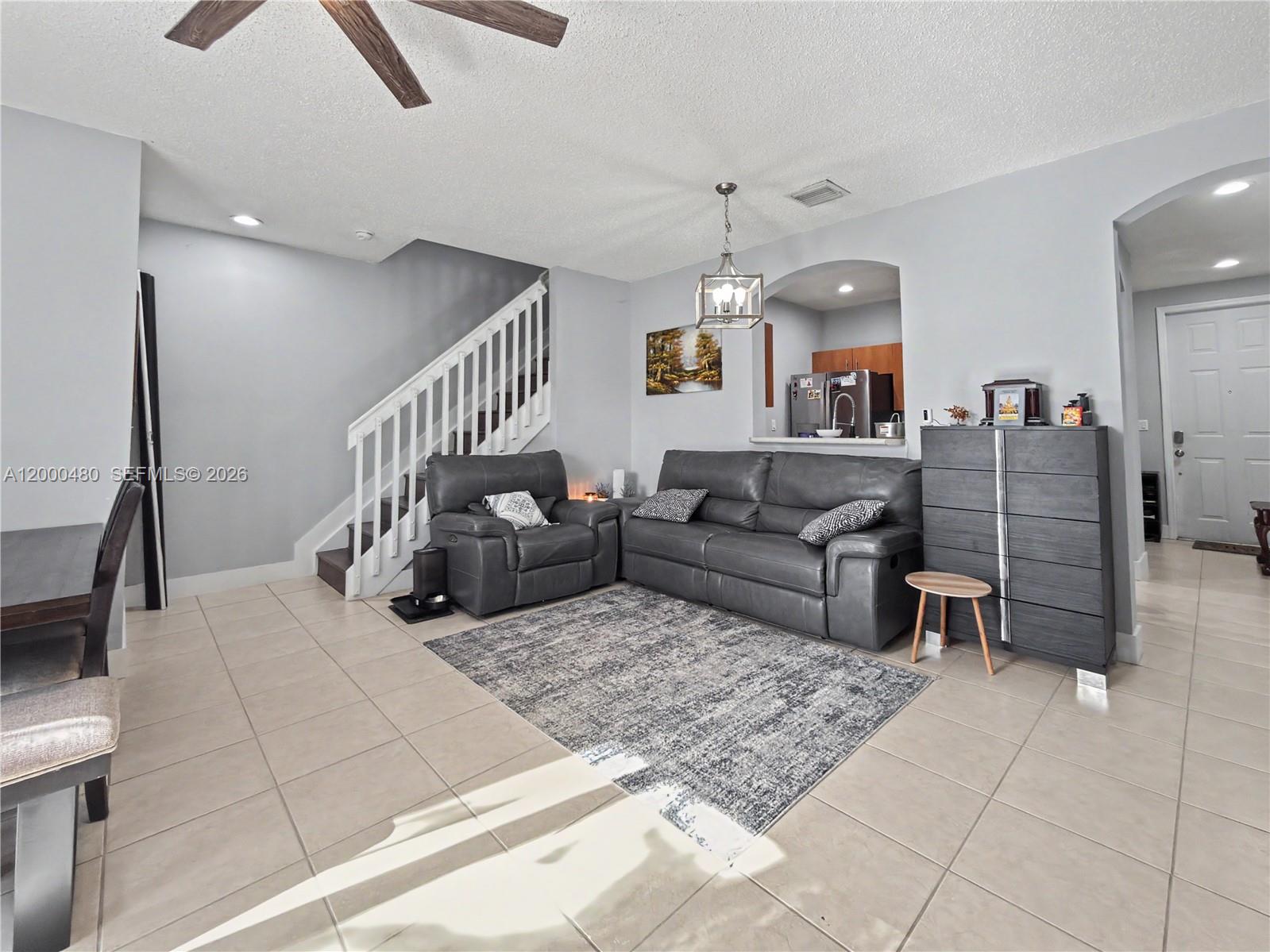 A living room features gray tile floors, a staircase, and a gray leather sofa set — 1033 NE 42nd Pl, Homestead FL 33033, HOMESTEAD, FL