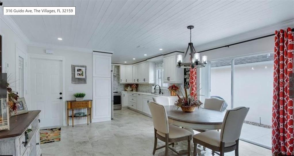 A bright kitchen and dining area features white cabinetry, tile flooring, and a wooden ceiling — 316 GUIDO AVENUE, LADY LAKE, FL