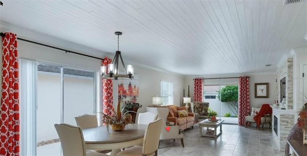 A dining area and living room with white plank ceilings, tile floors, and red curtains — 316 GUIDO AVENUE, LADY LAKE, FL