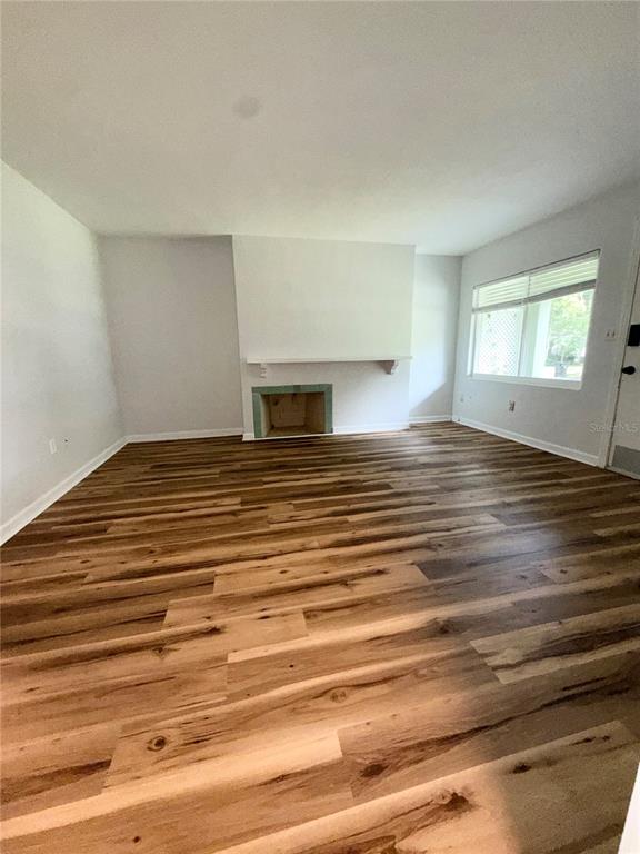 A living room features wood-look flooring, white walls, and an unfinished fireplace hearth — 1016 ALBA DRIVE UNIT 1016, ORLANDO, FL