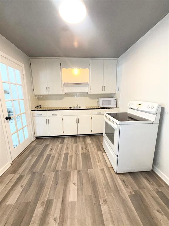 A kitchen features white cabinets, a white stove, and light-colored wood-look flooring — 1016 ALBA DRIVE UNIT 1016, ORLANDO, FL