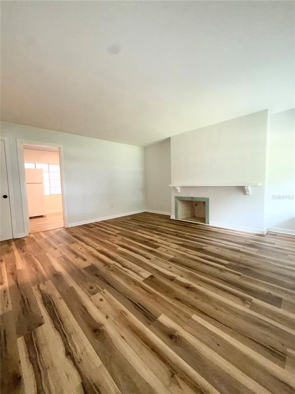 A living room with wood-look flooring, white walls, and a fireplace with a mantel — 1016 ALBA DRIVE UNIT 1016, ORLANDO, FL