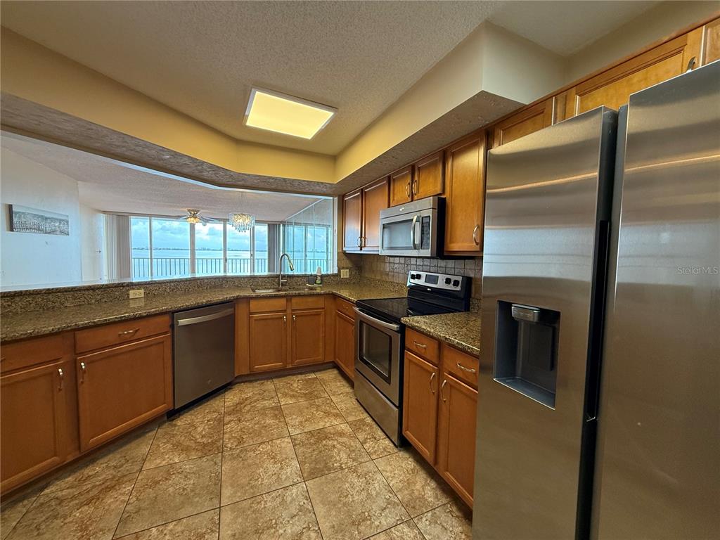 A kitchen with wood cabinets, granite countertops, stainless steel appliances, and a water view — 5155 ISLA KEY BOULEVARD S UNIT 307, ST PETERSBURG, FL