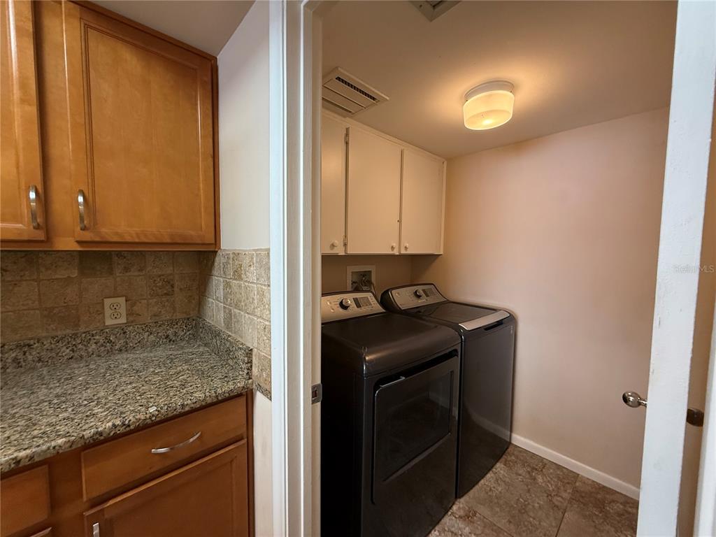 A laundry room with dark appliances and white cabinets sits adjacent to a kitchen area — 5155 ISLA KEY BOULEVARD S UNIT 307, ST PETERSBURG, FL