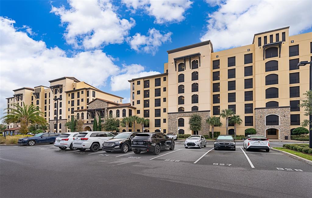 A multi-story beige apartment building with stone accents stands behind a paved parking lot — 16300 COUNTY ROAD 455 UNIT 602, MONTVERDE, FL