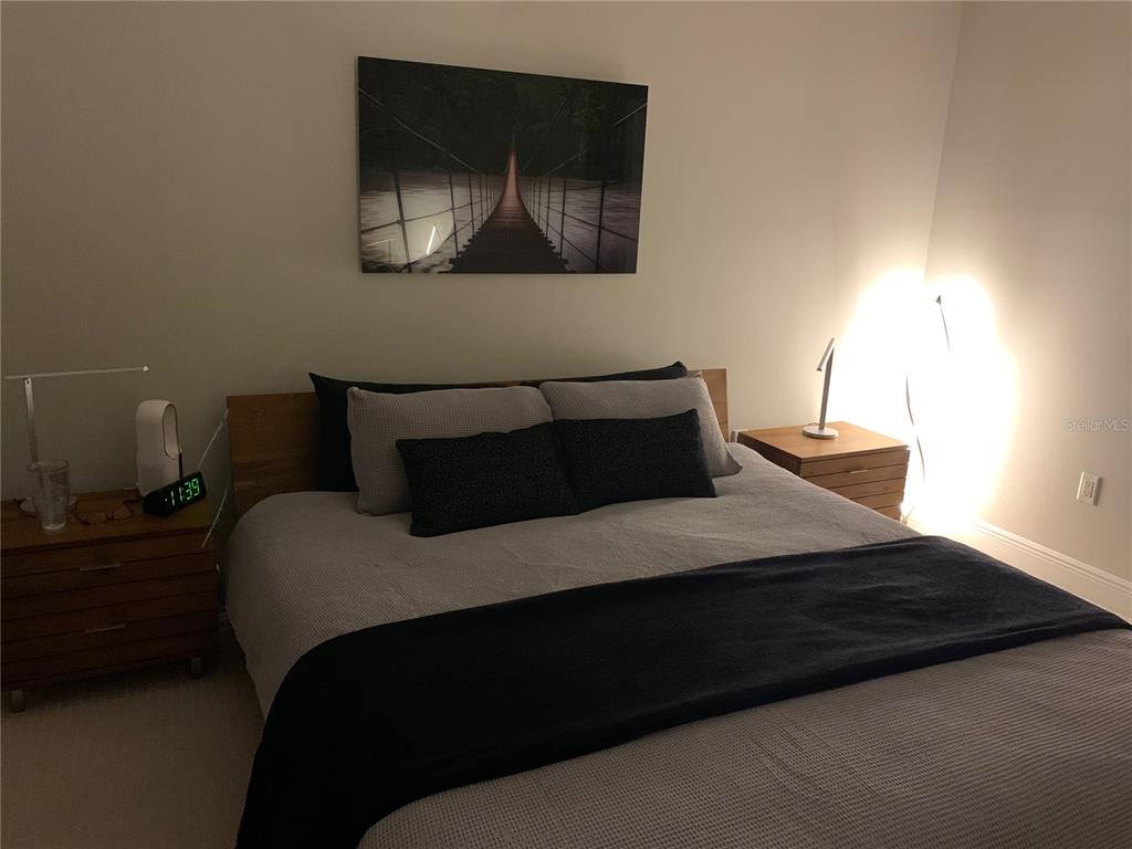 A bedroom features a bed with grey bedding, two wooden nightstands, and wall art — 16300 COUNTY ROAD 455 UNIT 602, MONTVERDE, FL