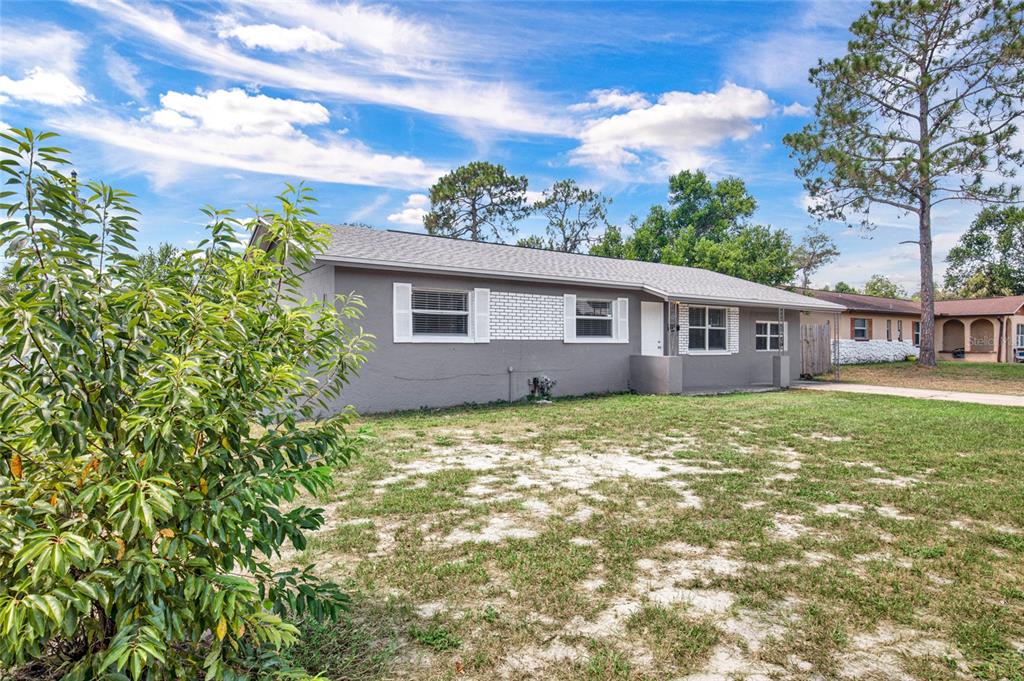 A gray single-story house with white shutters and a brick accent wall under a blue sky — 4822 OKEEFE STREET, ORLANDO, FL