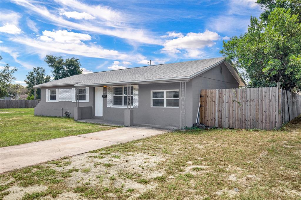 A single-story gray house with a concrete driveway and a wooden fence on the side — 4822 OKEEFE STREET, ORLANDO, FL
