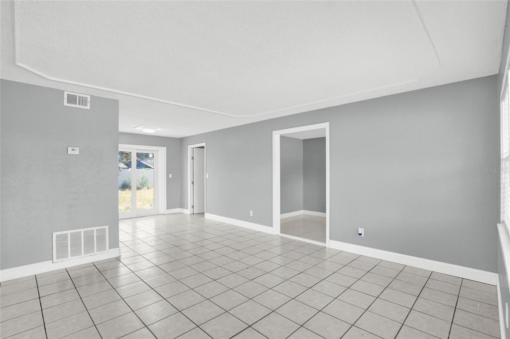 An empty room with gray walls, white trim, and light-colored tile flooring — 4822 OKEEFE STREET, ORLANDO, FL