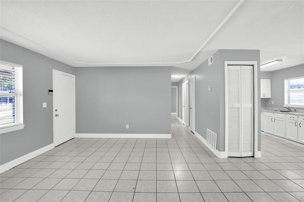A living area with gray walls, white trim, and light-colored tile flooring — 4822 OKEEFE STREET, ORLANDO, FL