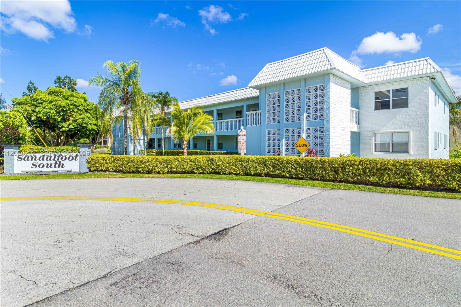 A low-rise apartment building with a white exterior and decorative concrete blocks sits behind landscaping — 9780 N Marina Blvd # 424, Boca Raton FL 33428, BOCA RATON, FL