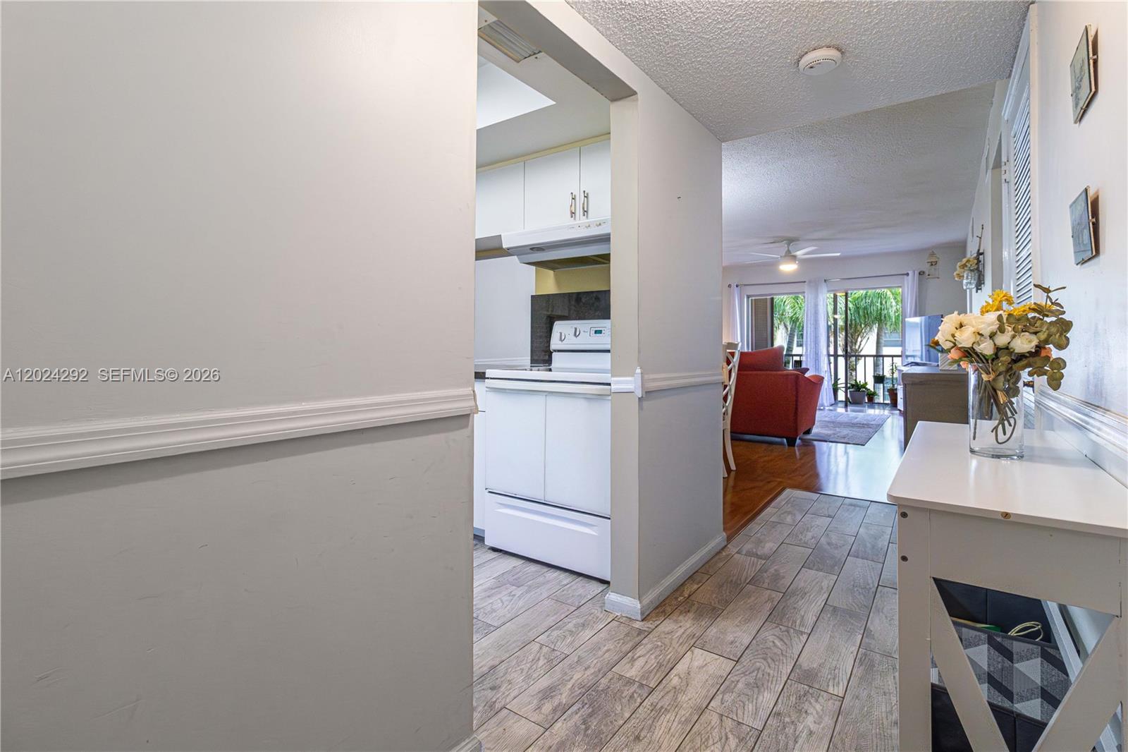 A view from a hallway looking into a kitchen and a living area beyond — 9780 N Marina Blvd # 424, Boca Raton FL 33428, BOCA RATON, FL