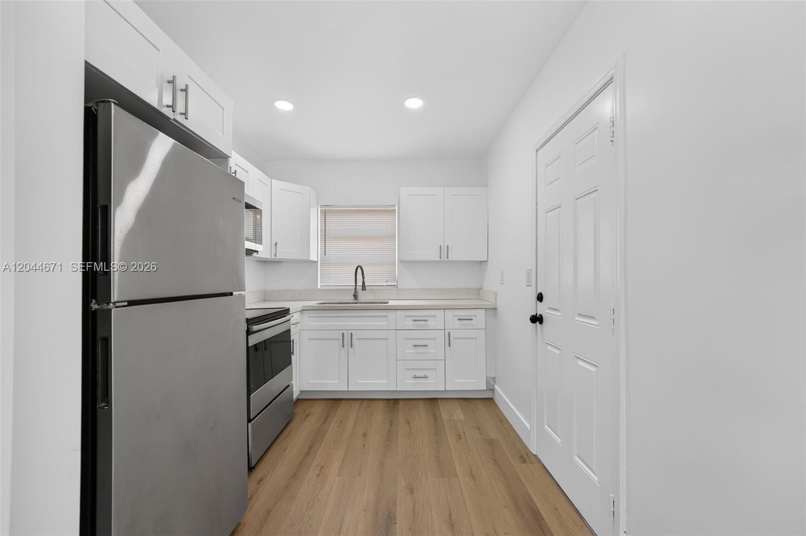 A kitchen features white cabinets, stainless steel appliances, and light wood-look flooring — 1900 SW 6th St SW 6th St # 6, Miami FL 33135, MIAMI, FL
