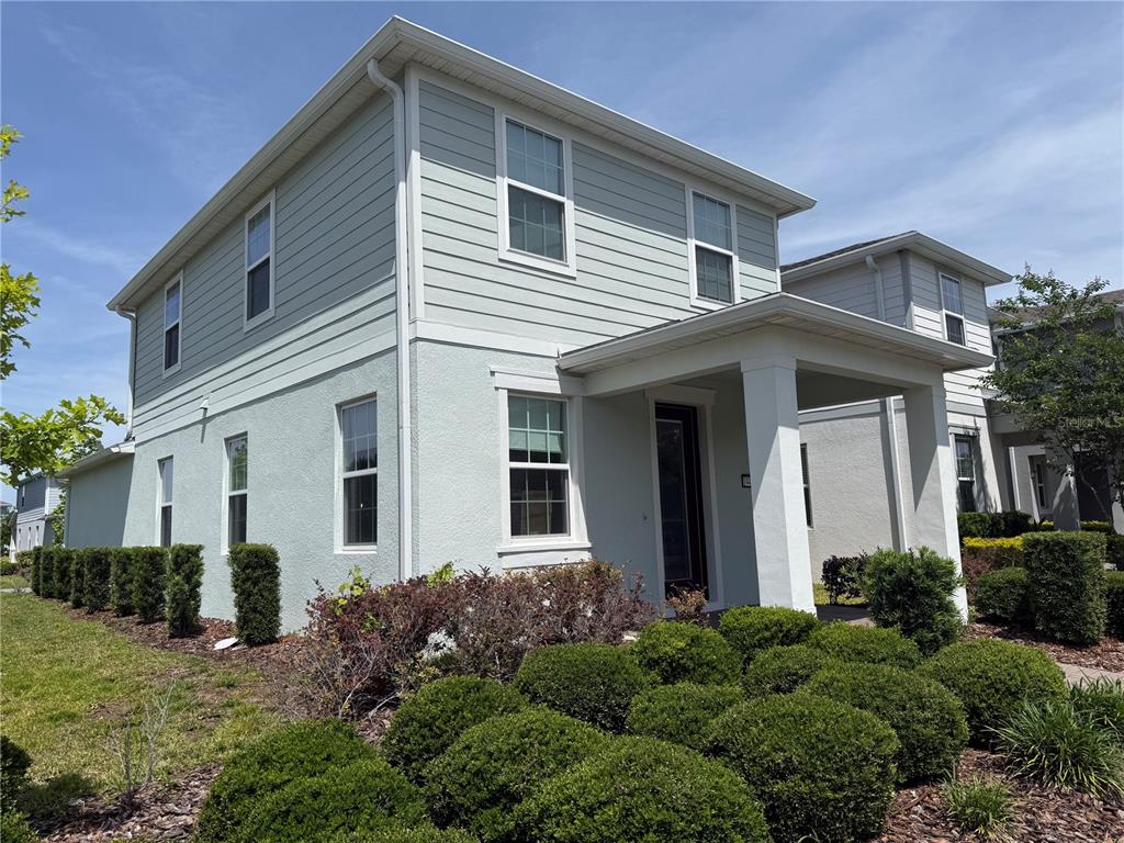 A two-story house with light green siding and a covered front porch entrance — 14486 SAPELO BEACH DRIVE, ORLANDO, FL