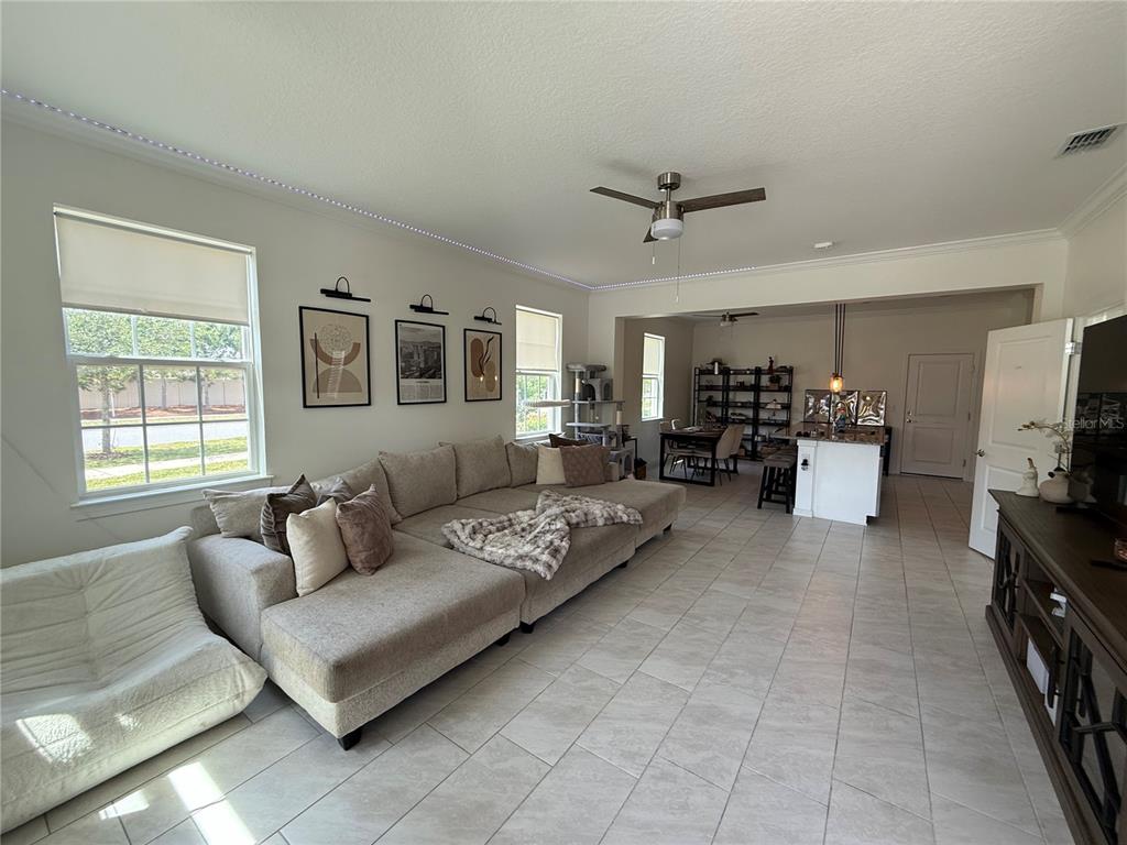 A spacious living room with tile floors, a large sectional sofa, and an open kitchen — 14486 SAPELO BEACH DRIVE, ORLANDO, FL