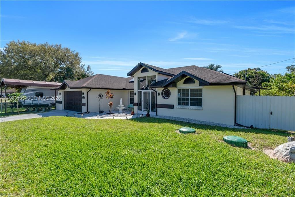 A single-story house with a brown roof, beige stucco walls, and a large front lawn — 2504 E 7th ST, Lehigh Acres FL 33936, LEHIGH ACRES, FL