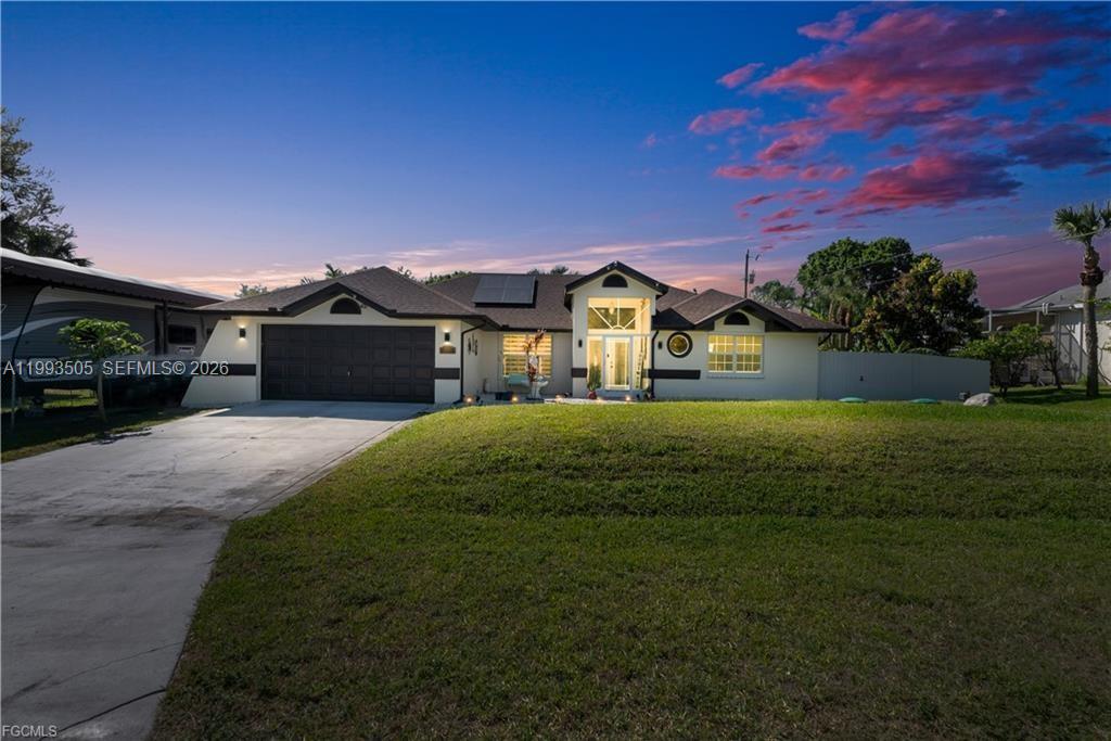 A single-story house with a two-car garage and a paved driveway at sunset — 2504 E 7th ST, Lehigh Acres FL 33936, LEHIGH ACRES, FL