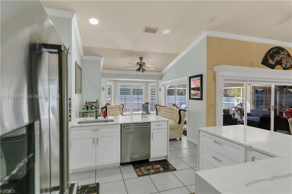 A kitchen features white cabinetry, stainless steel appliances, and a view into a living area — 2504 E 7th ST, Lehigh Acres FL 33936, LEHIGH ACRES, FL