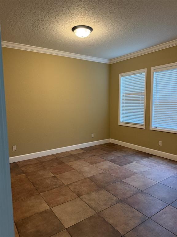 An empty room with tan walls, tile flooring, crown molding, and two windows with blinds — 3613 S SUMMERLIN AVENUE, ORLANDO, FL