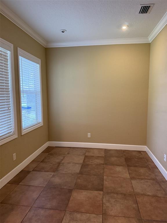 An empty room with tan walls, brown tile flooring, and two windows with white blinds — 3613 S SUMMERLIN AVENUE, ORLANDO, FL