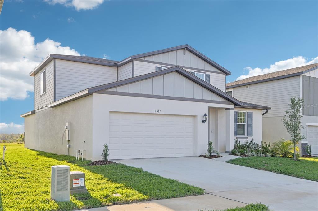 A two-story house with a white stucco garage, light-colored siding, and a concrete driveway — 12597 HOMELAND DRIVE, DADE CITY, FL