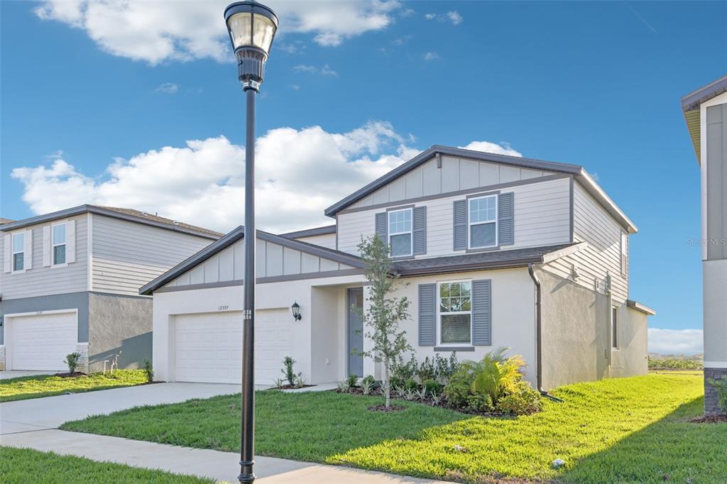 A two-story suburban house with a white garage, gray shutters, and a front lawn — 12597 HOMELAND DRIVE, DADE CITY, FL