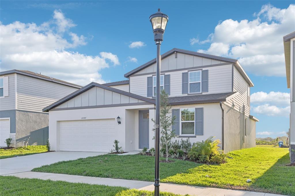 A two-story suburban house with a white stucco facade, gray shutters, and a two-car garage — 12597 HOMELAND DRIVE, DADE CITY, FL