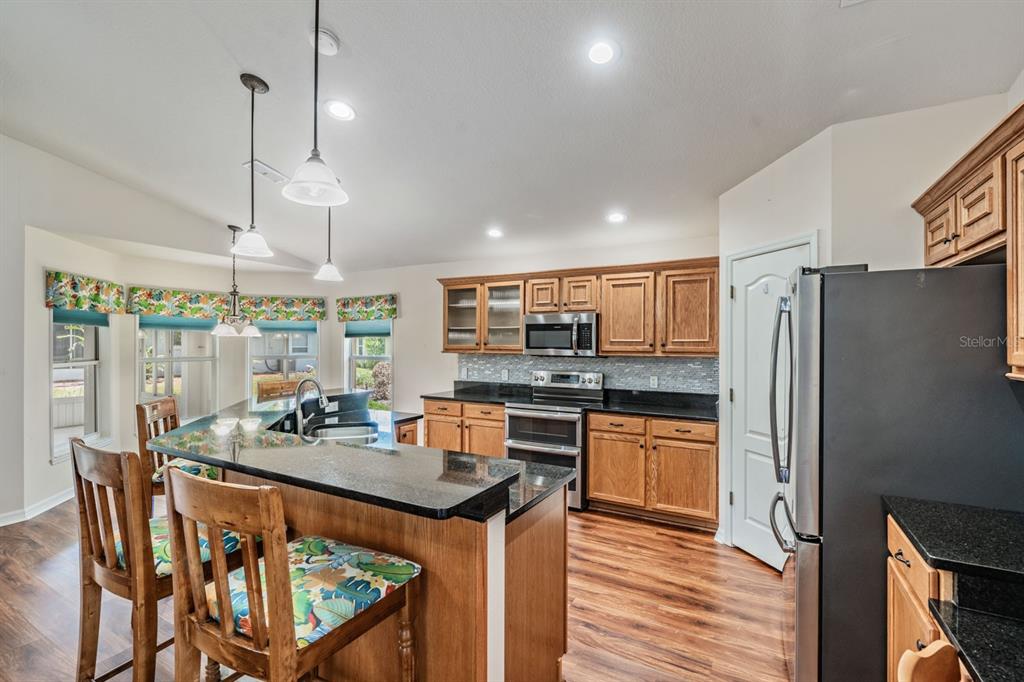 A kitchen features wood cabinets, black countertops, stainless steel appliances, and a breakfast bar — 11709 SPINDRIFT LOOP, HUDSON, FL