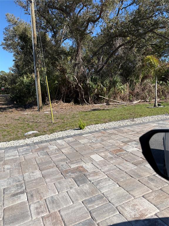 A paved driveway leads to a grassy lot with trees and a utility pole — 2049 CORNELIUS BOULEVARD, PORT CHARLOTTE, FL