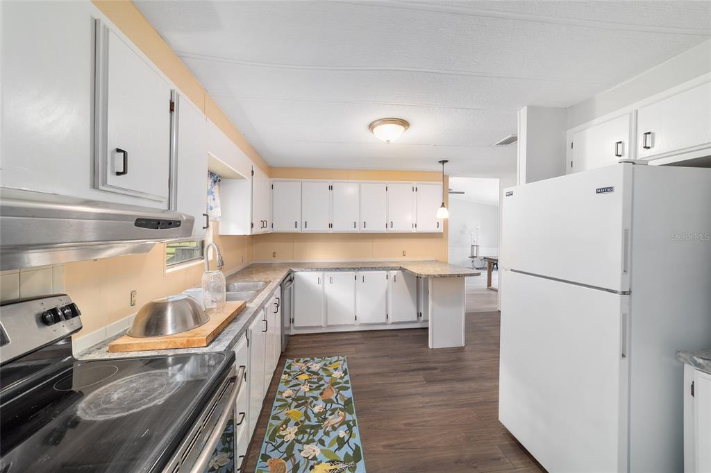 A kitchen with white cabinets, a white refrigerator, a black stove, and wood-look flooring — 3371 NW 120TH AVENUE, OCALA, FL