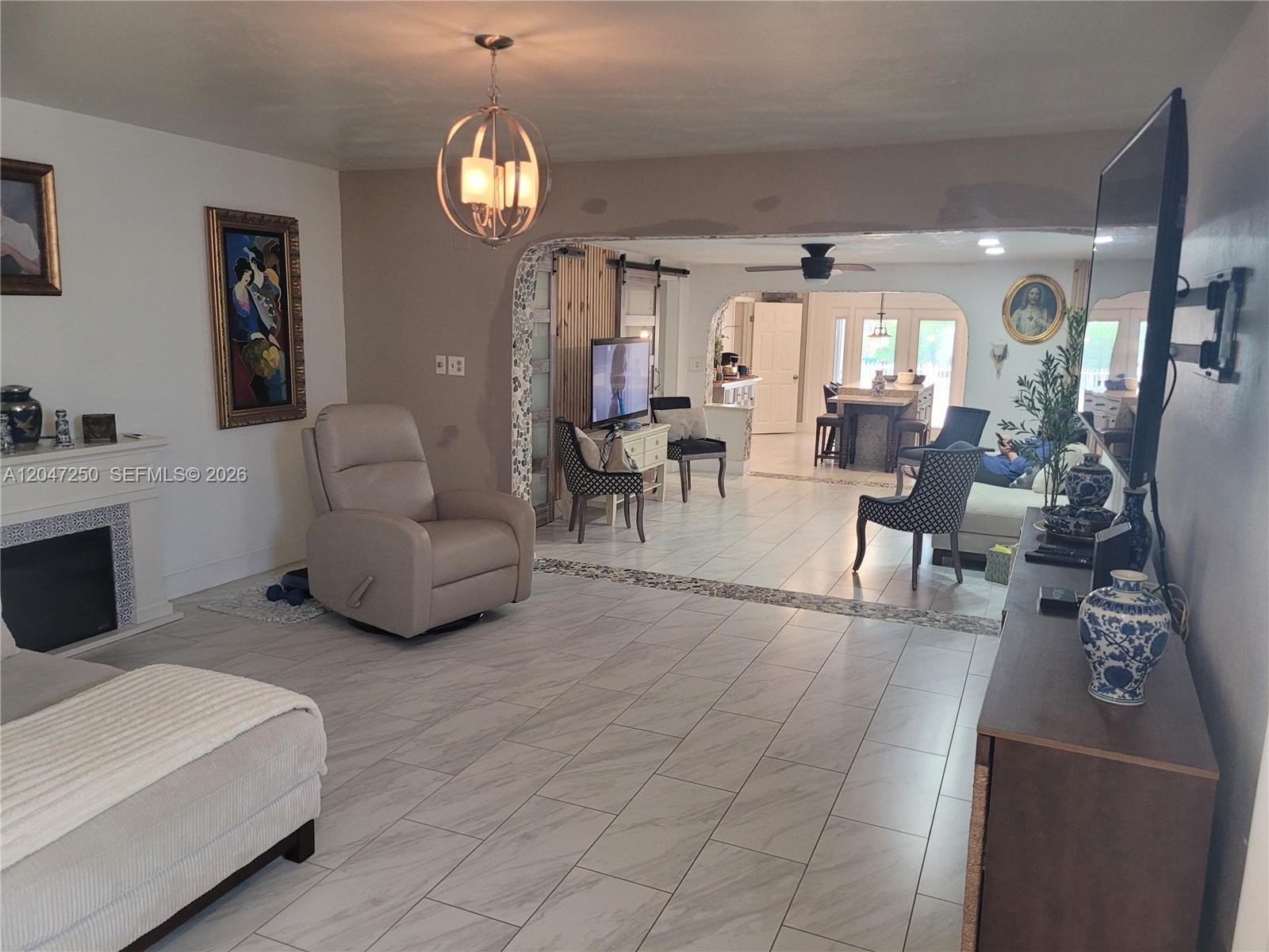 A living room with light tile flooring, a fireplace, and an open-concept kitchen beyond — 6691 W 15th Ct # 1, Hialeah FL 33012, HIALEAH, FL