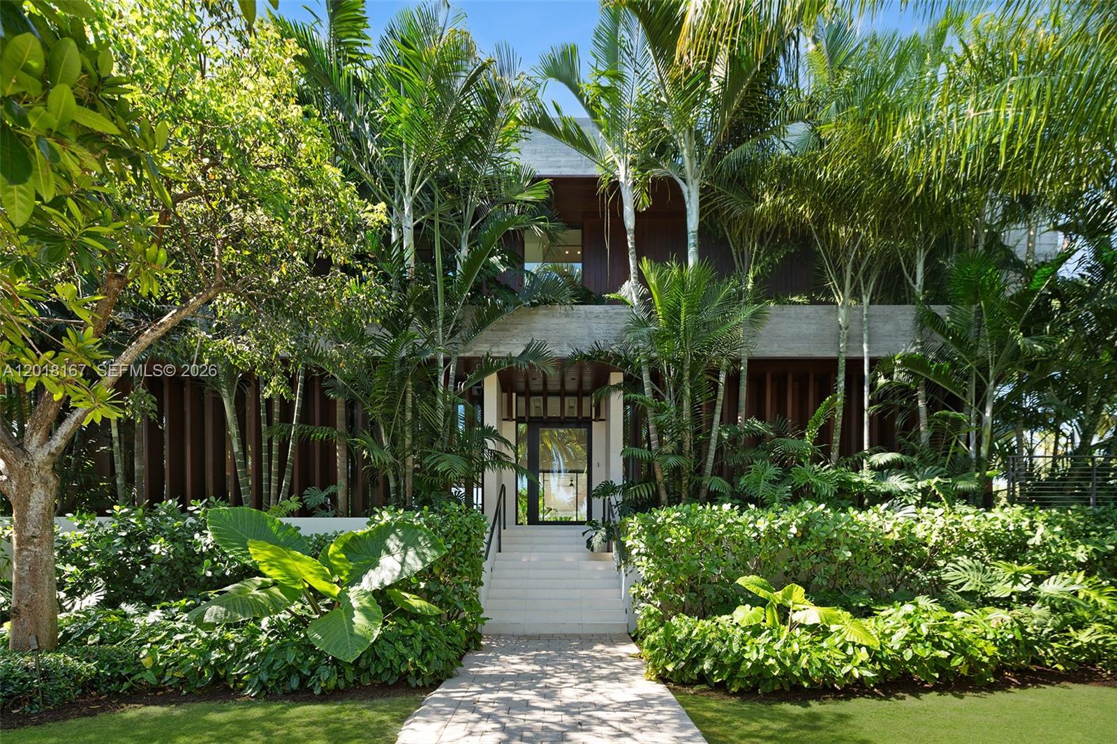 A modern house exterior features concrete accents, vertical wood slats, and lush tropical landscaping — 1420 W 23rd St, Miami Beach FL 33140, MIAMI BEACH, FL