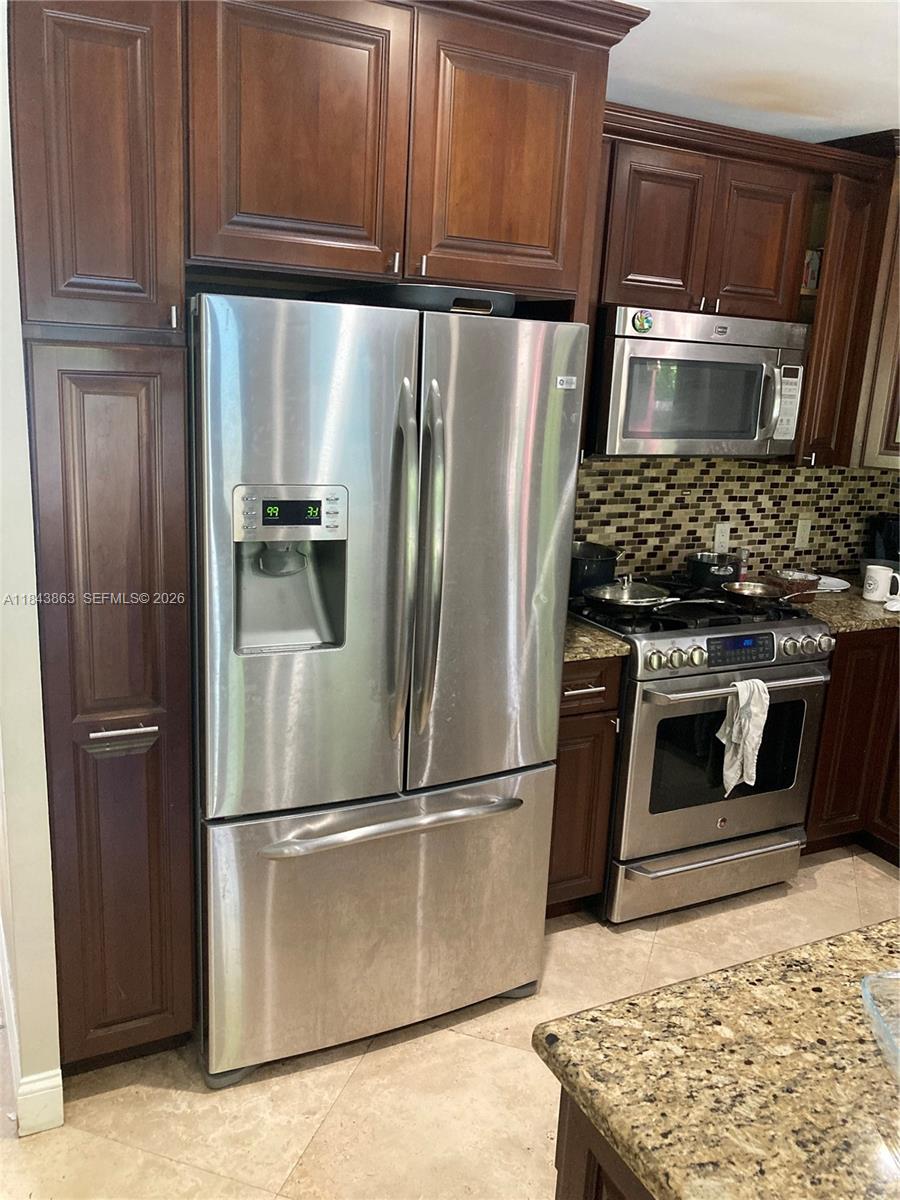 A kitchen features dark wood cabinetry, stainless steel appliances, and a granite countertop — 10801 SW 123rd St, Miami FL 33176, MIAMI, FL