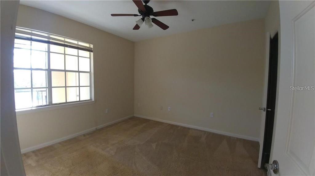 An empty bedroom features beige carpet, light-colored walls, a ceiling fan, and a large window — 2652 ROBERT TRENT JONES DRIVE UNIT 534, ORLANDO, FL