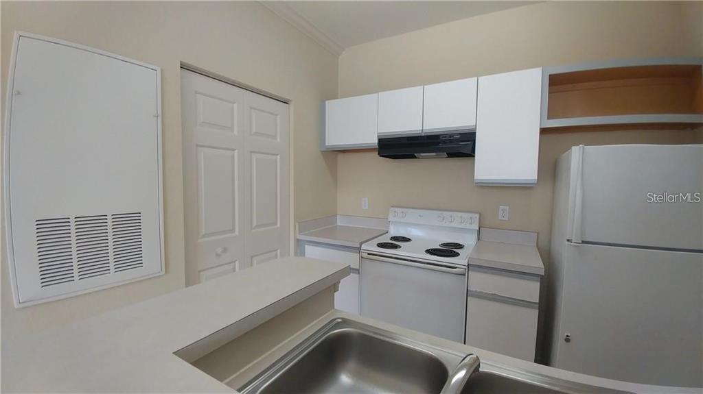 A kitchen features white cabinets, white appliances, a double sink, and a breakfast bar — 2652 ROBERT TRENT JONES DRIVE UNIT 534, ORLANDO, FL