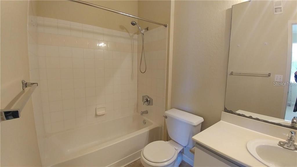 A bathroom features a white bathtub with a showerhead, a toilet, and a vanity mirror — 2652 ROBERT TRENT JONES DRIVE UNIT 534, ORLANDO, FL