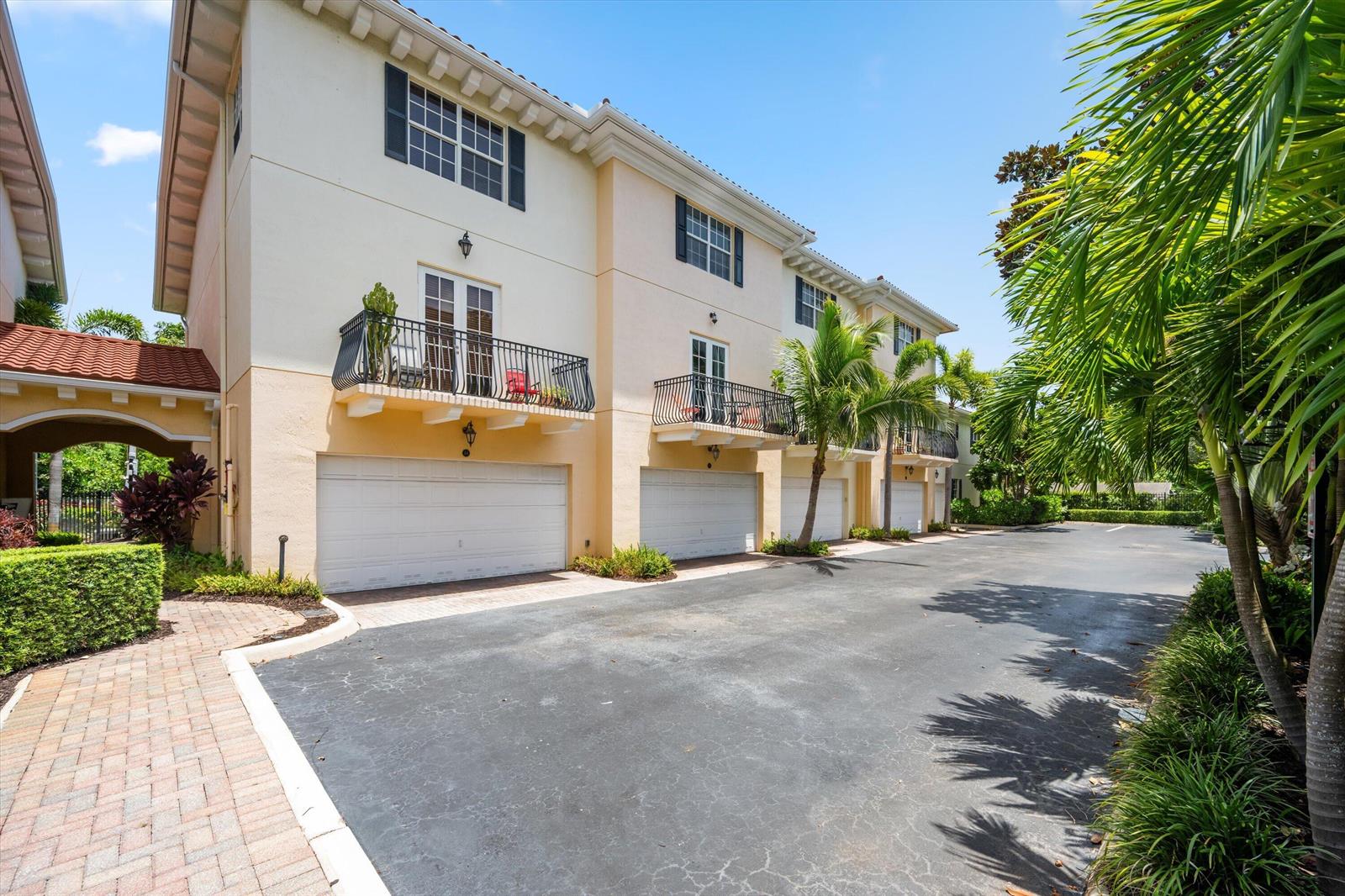 A row of three-story townhomes with beige stucco walls, balconies, and attached garages — 2502 N Dixie Highway # 52, FL 33460, FL