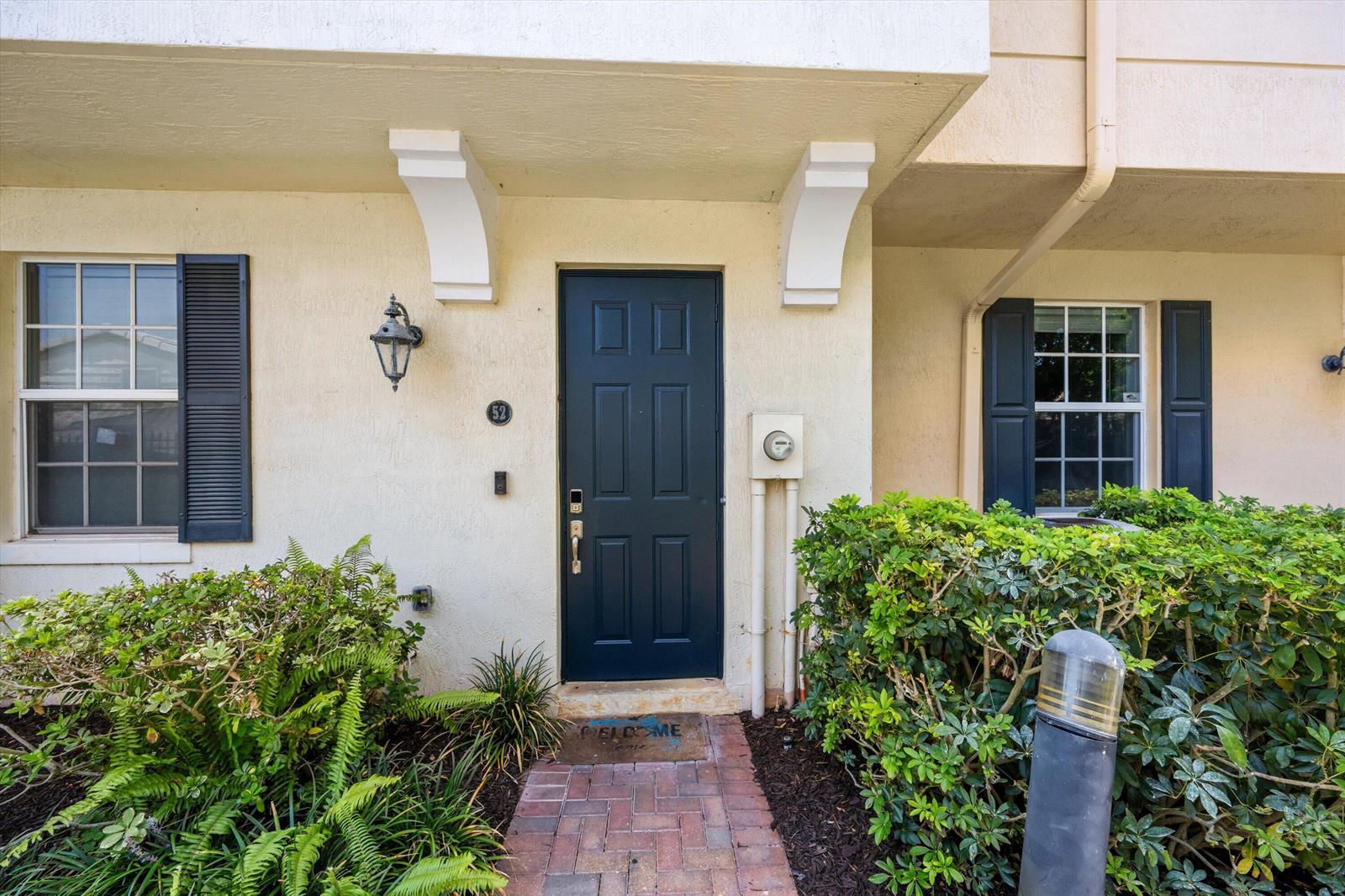 The exterior of a residential unit features a dark blue front door and brick walkway — 2502 N Dixie Highway # 52, FL 33460, FL